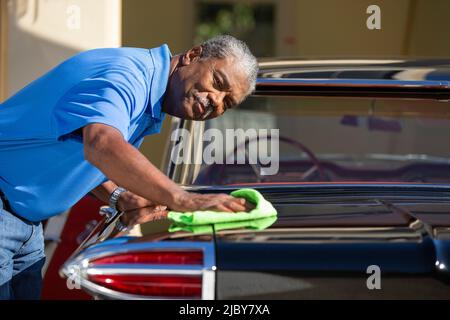 Older man drying off his classic car Stock Photo