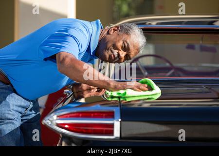 Older man drying off 1960 Oldsmobile Super 88 Holiday Sport Sedan after detailing Stock Photo