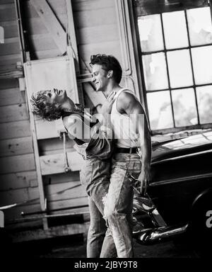 Young mechanic and his girlfriend cuddlind and laughing in workshop Stock Photo