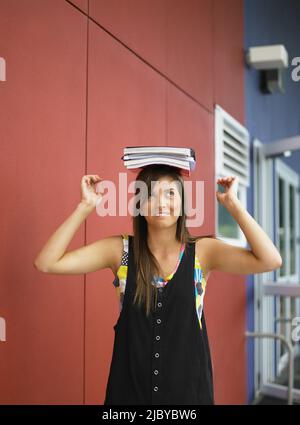 Young female student balancing books on her head Stock Photo
