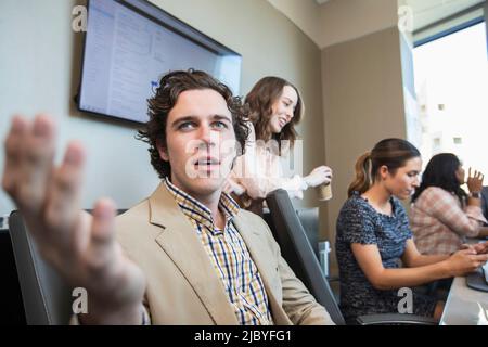 Young man having discussion in conference room with co-workers working in background Stock Photo