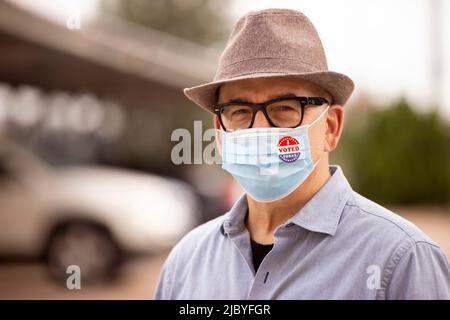 Older Caucasian male with glasses and fedora, wearing a mask and an I Voted Today sticker on the mask Stock Photo