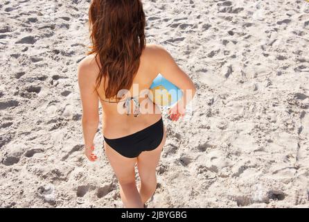 Back view of young volleyball player holding ball standing on the sand Stock Photo