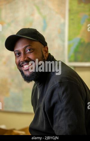 Portrait of middle aged bearded black man wearing a baseball hat looking towards camera smiling Stock Photo