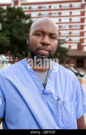 Portrait of middle aged man with beard and a bald head wearing scrubs standing outside looking at camera Stock Photo