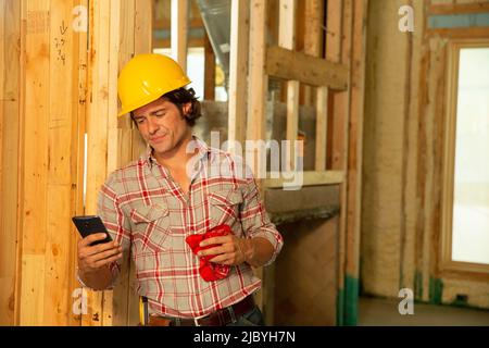 Construction worker wearing hard-hat on job site using mobile phone Stock Photo