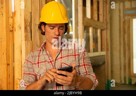 Construction worker wearing hard-hat on job site using mobile phone Stock Photo