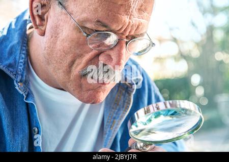 Older man using magnifying glass Stock Photo