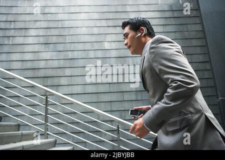 Chinese businessman with cell phone going up stairs Stock Photo