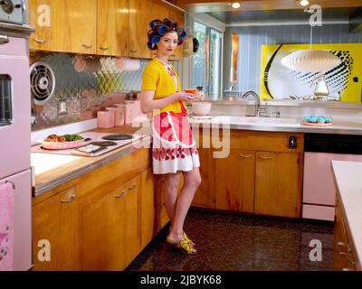 https://l450v.alamy.com/450v/2jbyk68/vintage-styled-woman-holding-a-coffee-looking-into-camera-in-a-mid-century-house-2jbyk68.jpg