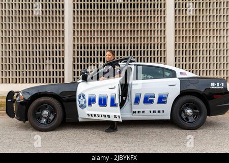 Policewoman standing in door of Police car looking towards camera Stock Photo