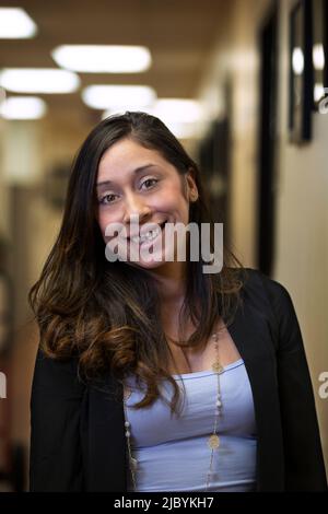 Portrait of young woman smiling in hallway of office building Stock Photo