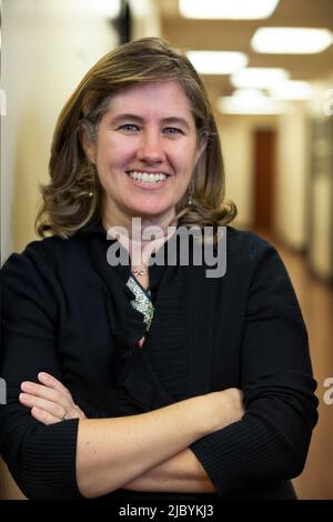 Portrait of middle aged woman with arms crossed smiling in hallway of office building Stock Photo