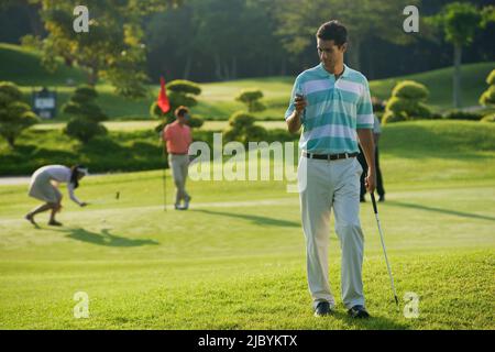 Golfer text messaging on cell phone Stock Photo