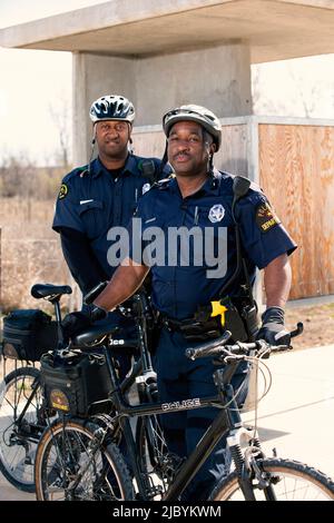 Portrait of Bicycle Police officers standing outside with their bikes looking towards camera smiling Stock Photo