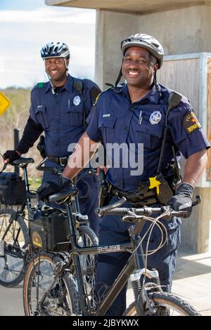 Portrait of Bicycle Police officers standing outside with their bikes looking towards camera smiling Stock Photo
