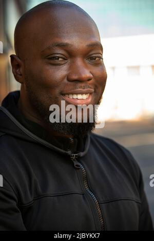 Portrait of young man with beard and a bald head standing outside looking at camera Stock Photo
