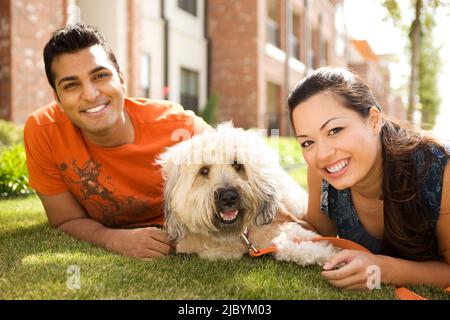 Couple with dog laying on grass Stock Photo