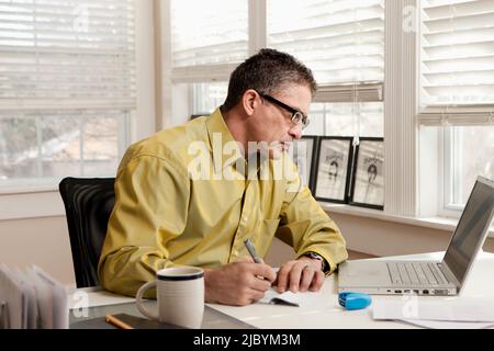 Hispanic man paying bills at desk Stock Photo
