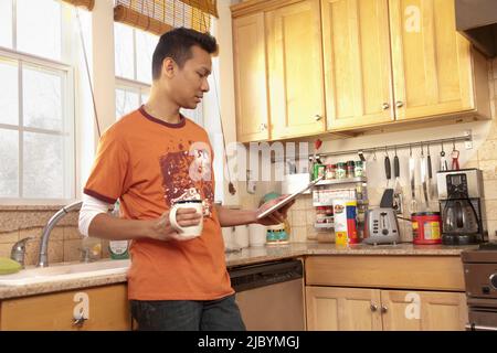 Malaysian man using digital tablet in kitchen Stock Photo