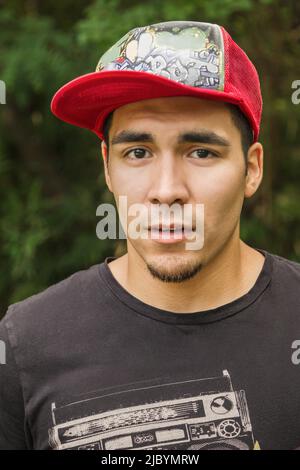 Serious Hispanic man in baseball cap Stock Photo