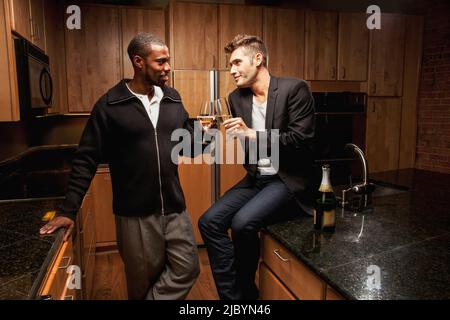 Gay couple drinking wine in kitchen Stock Photo