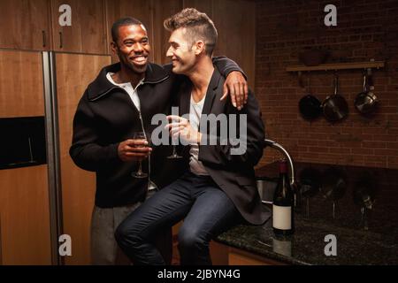 Gay couple drinking wine in kitchen Stock Photo