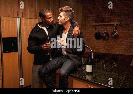 Gay couple drinking wine in kitchen Stock Photo