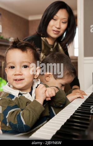 Asian mother teaching sons to play piano Stock Photo