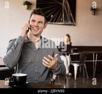 Caucasian man talking on cell phone in cafe Stock Photo