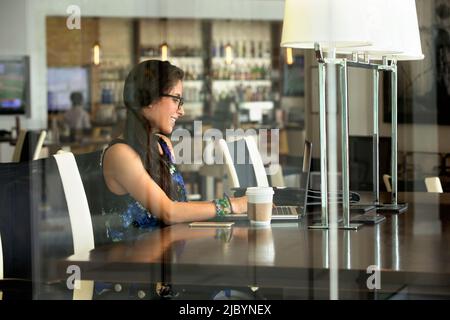 Hispanic woman using laptop in coffee shop Stock Photo