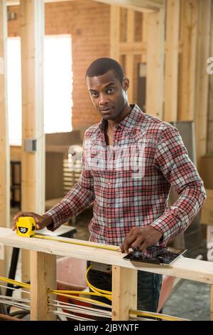 Worker measuring wood at construction site Stock Photo