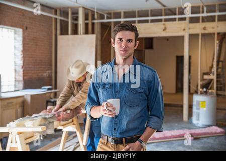 Man drinking coffee at construction site Stock Photo