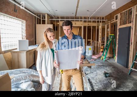 Caucasian couple reading blueprints at construction site Stock Photo