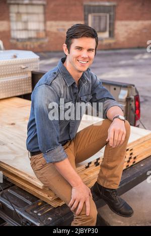 Caucasian man sitting on truck bed Stock Photo