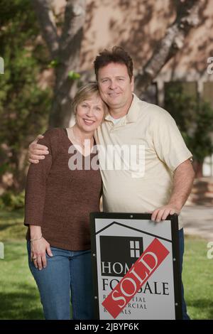 Couple standing in yard with sold sign Stock Photo - Alamy