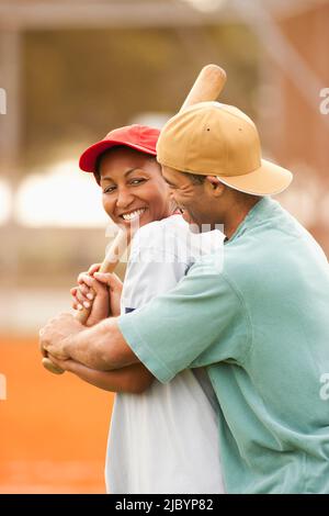 Man teaching girlfriend to play baseball Stock Photo