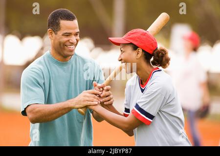 Man teaching girlfriend to play baseball Stock Photo