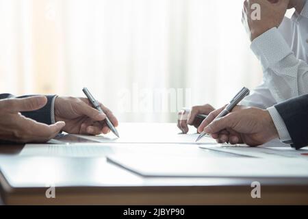 Close up of three businessmen or analysts in a meeting room discuss on business performance and financial statements Stock Photo