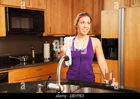 Hispanic woman drinking water after exercise Stock Photo