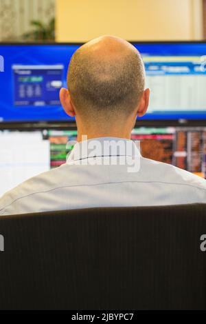 Rear view of trader using computer in office Stock Photo