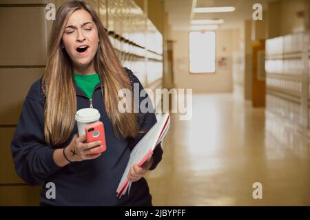 Middle Eastern student yawning in college hallway Stock Photo