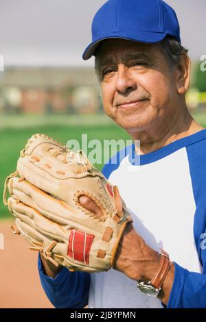 Senior Hispanic man playing on baseball team Stock Photo