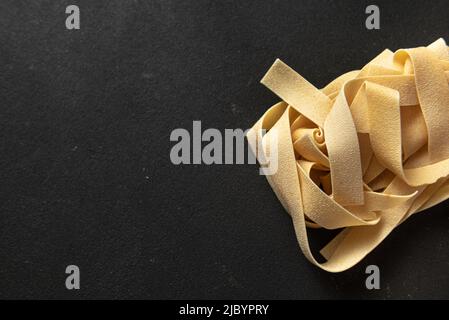 raw paste pappardelle on a dark background. Stock Photo