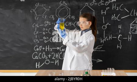 girl student scientist examining test flask with chemical reagent. Schoolgirl making experiment in chemistry class. Research and education in school Stock Photo