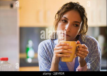 Hispanic woman drinking coffee in kitchen Stock Photo