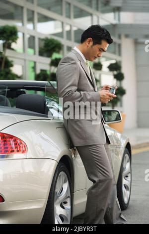 Chinese businessman text messaging on cell phone Stock Photo