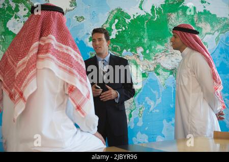 Middle Eastern businessman talking to men in traditional clothing Stock Photo