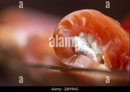 A roll of dried meat and soft cheese on a glass dish on the table. Festive table setting. Stock Photo