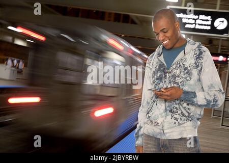 Black man text messaging on cell phone in subway Stock Photo
